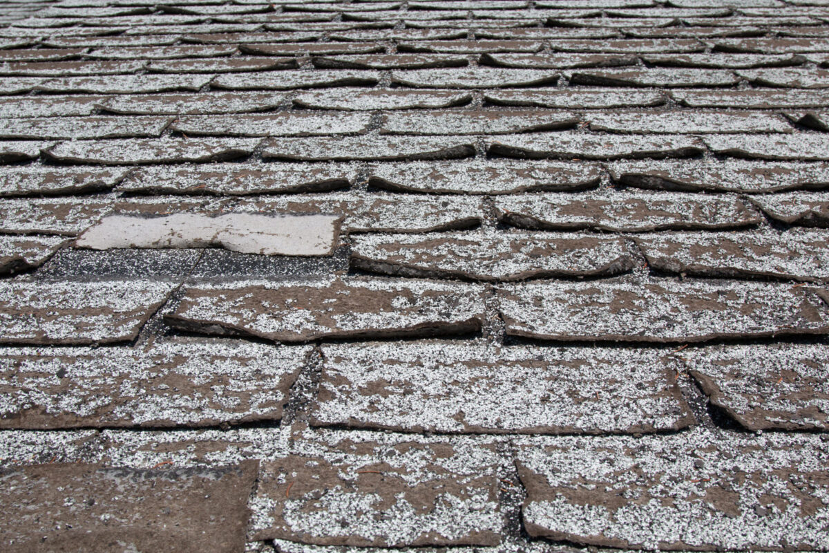 image of Old worn out asphalt shingles on the roof of a residential home.