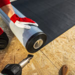 image of Roof Worker in Tampa Florida with Roll of EPDM Rubber Membrane Material Preparing to Cover Plywood Roof