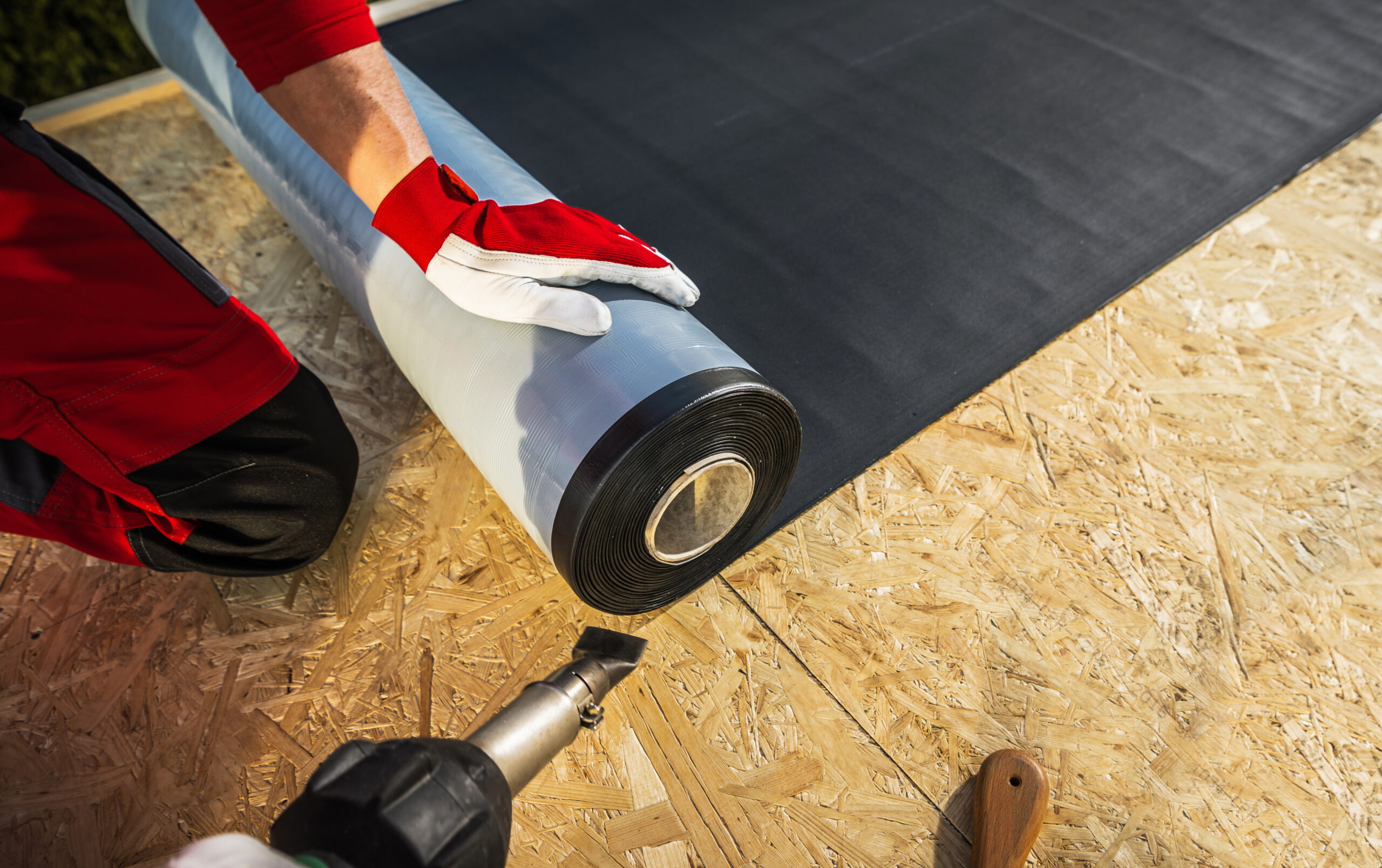 image of Roof Worker in Tampa Florida with Roll of EPDM Rubber Membrane Material Preparing to Cover Plywood Roof