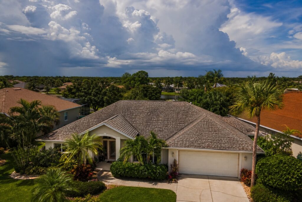 Aging asphalt shingle roof on a Florida suburban home in the Tampa Bay area with storm clouds building on the horizon