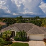Aging asphalt shingle roof on a Florida suburban home in the Tampa Bay area with storm clouds building on the horizon