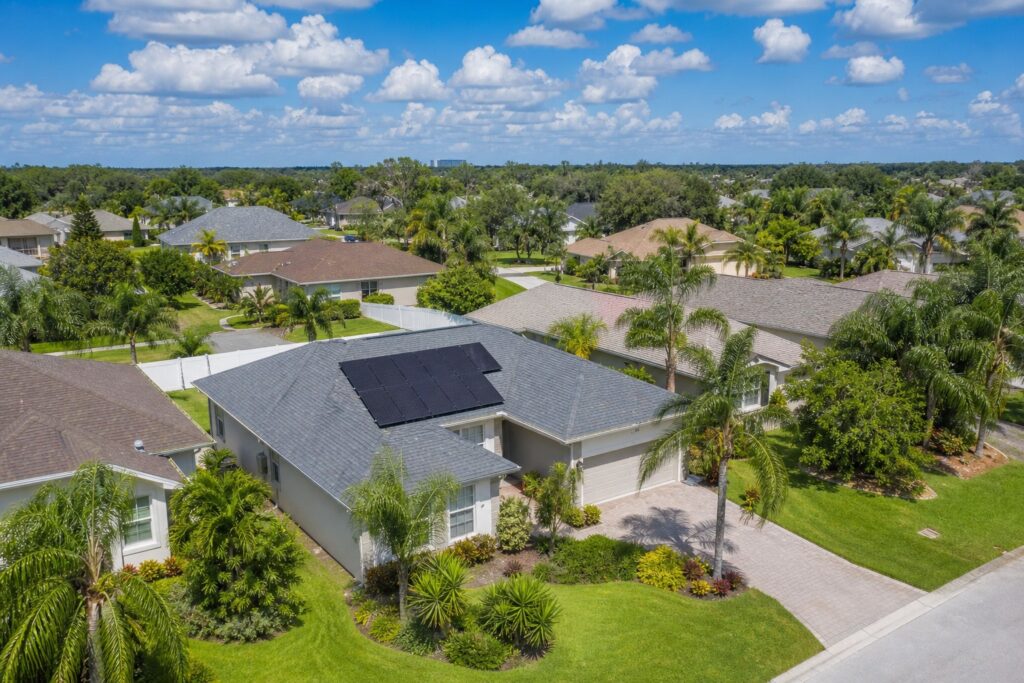 Aerial view of a Florida home with solar panels installed on the roof in a Tampa Bay suburban neighborhood with palm trees