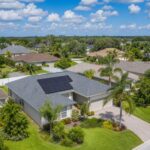 Aerial view of a Florida home with solar panels installed on the roof in a Tampa Bay suburban neighborhood with palm trees